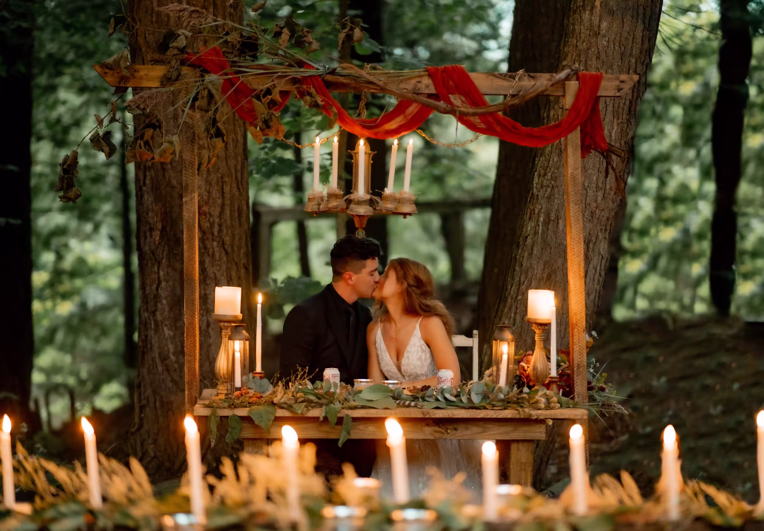 A bride and groom kissing between 2 trees