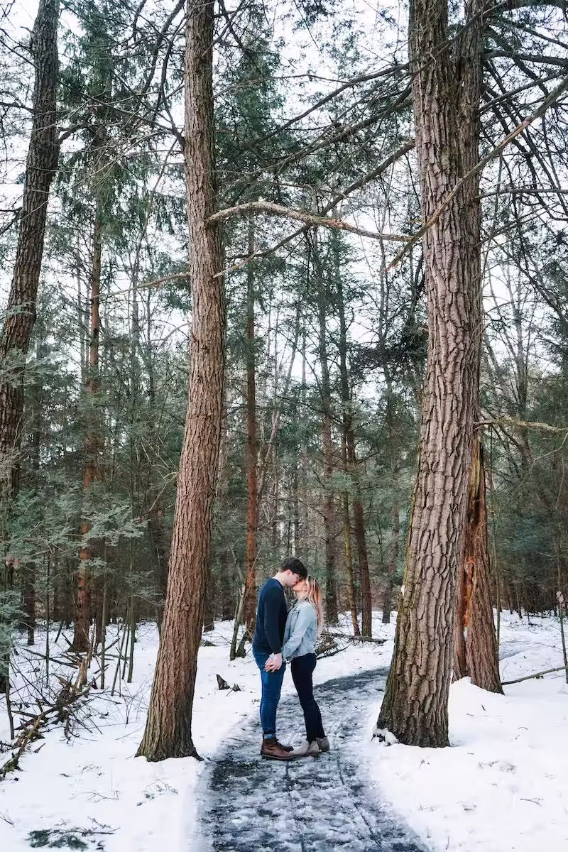 A bride and groom kissing between 2 trees